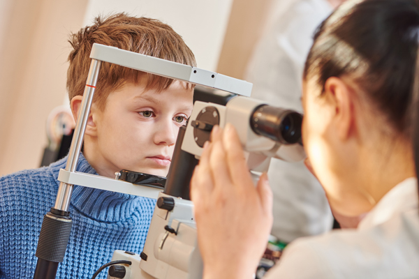 Child optometry. female optometrist optician doctor examines eyesight of little boy patient in eye ophthalmological clinic